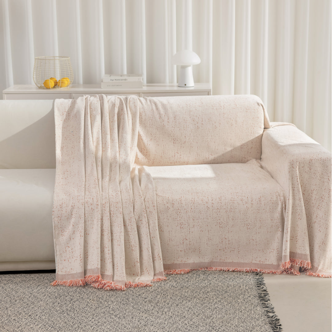 Cinnamon Iris Sprinkle Magic Sofa Blanket draped over a white sofa with a folded section and fringed edge