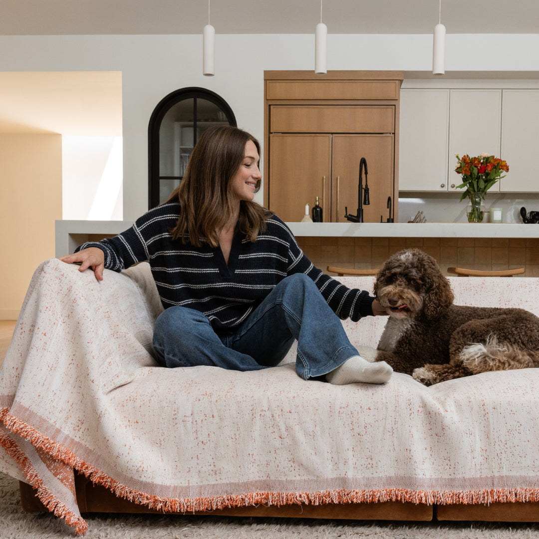 Woman and a brown curly-haired dog on a sofa draped in the Cinnamon Iris Sprinkle Magic Sofa Blanket