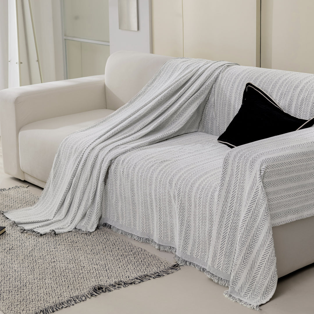 Caviar Lena Herring Magic Sofa Blanket draped over half of a cream sofa