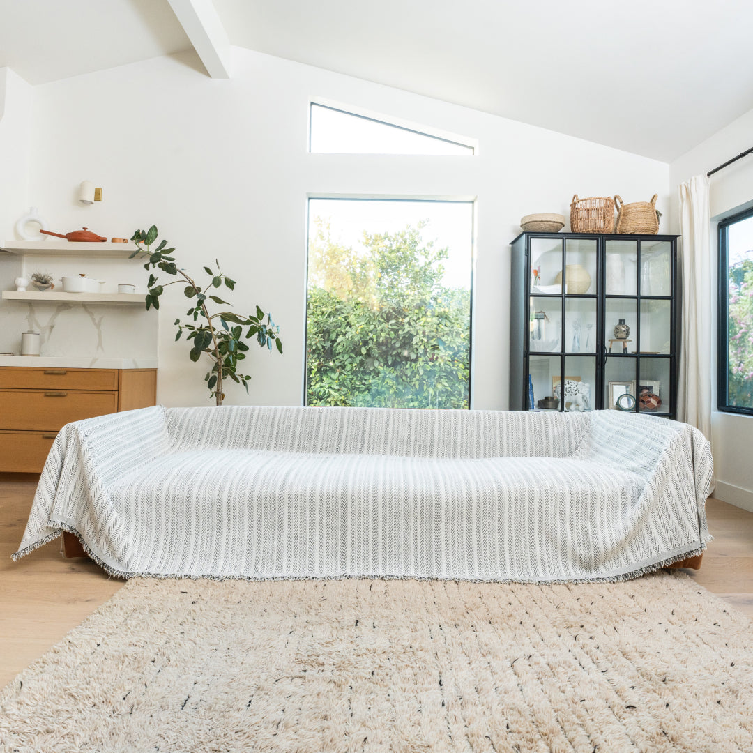 Caviar Lena Herring Magic Sofa Blanket covering a long sofa in a bright living room