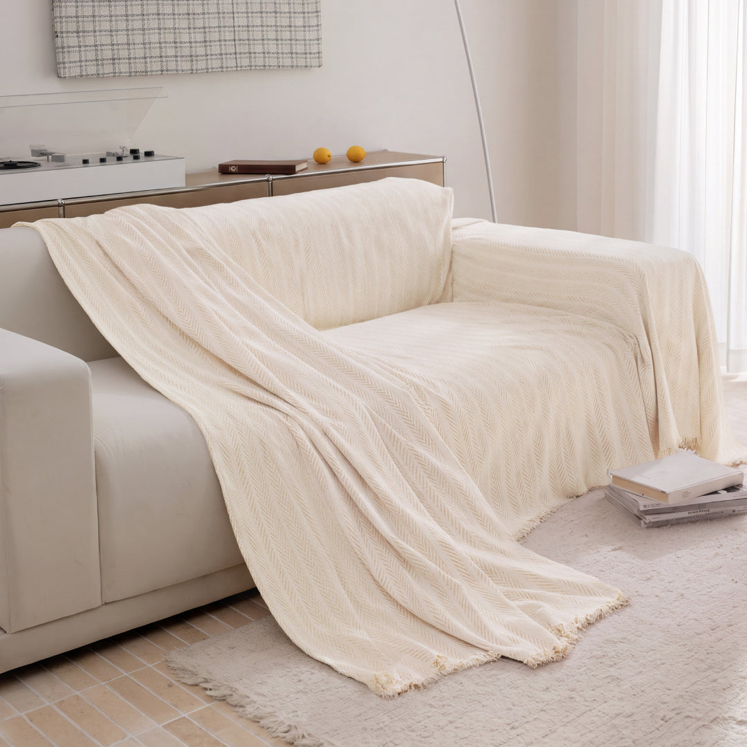 Latte Lena Herring Magic Sofa Blanket draped over half of a cream sofa