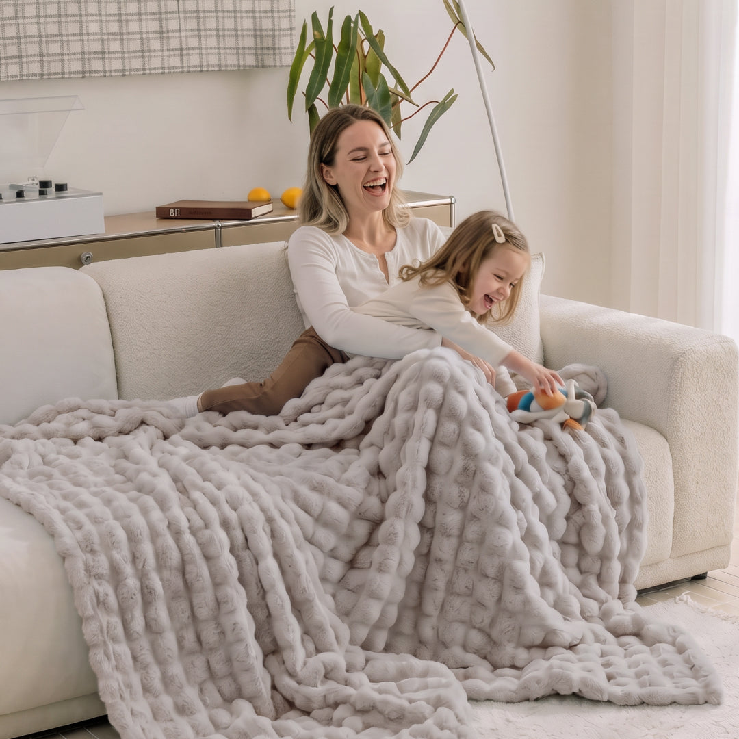 Person lounging on a sofa covered in the Oat Milk Nora Mink Magic Sofa Blanket