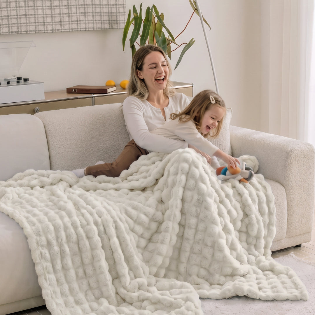 Person lounging on a sofa covered in the Vanilla Nora Mink Magic Sofa Blanket