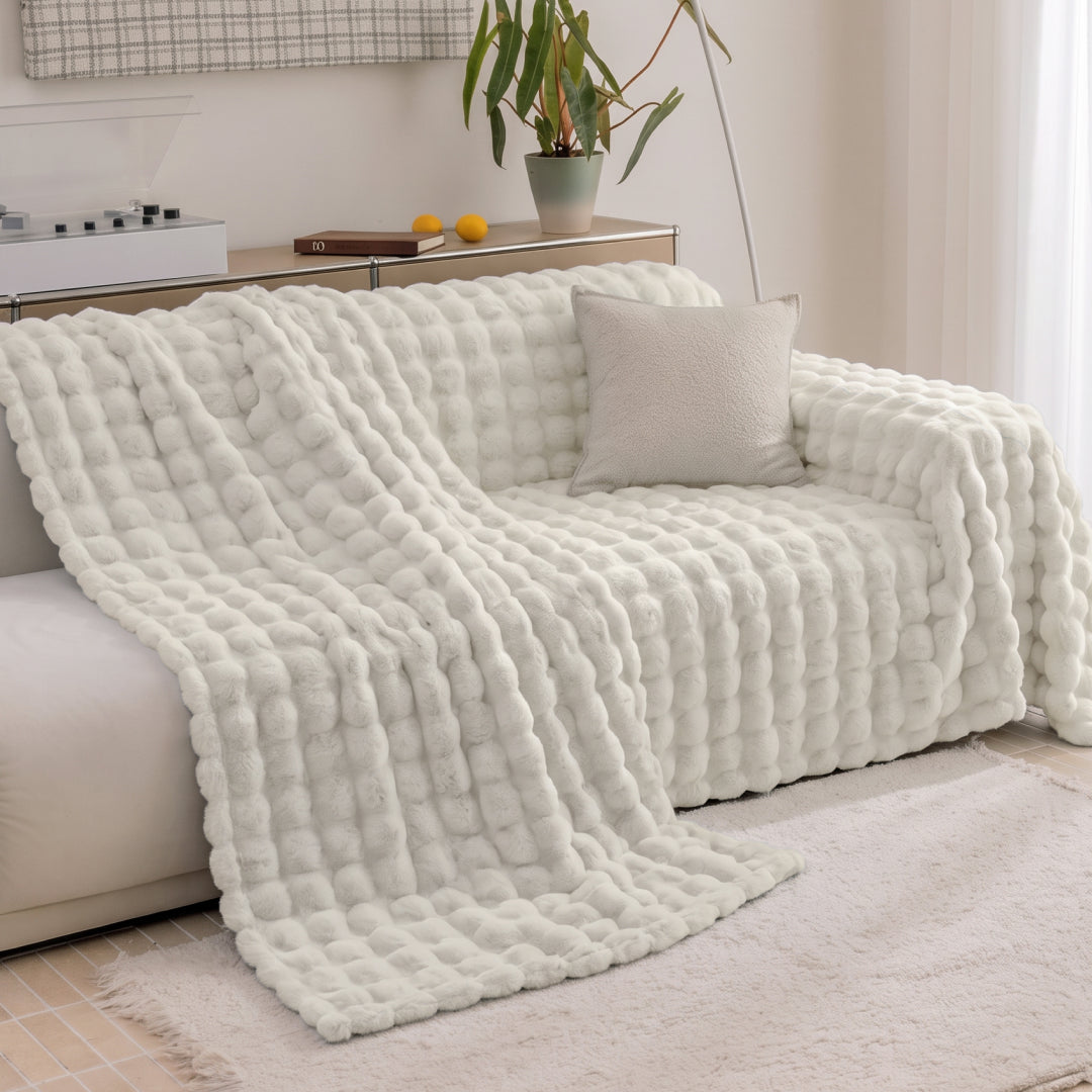 Vanilla Nora Mink Magic Sofa Blanket placed halfway over a sofa