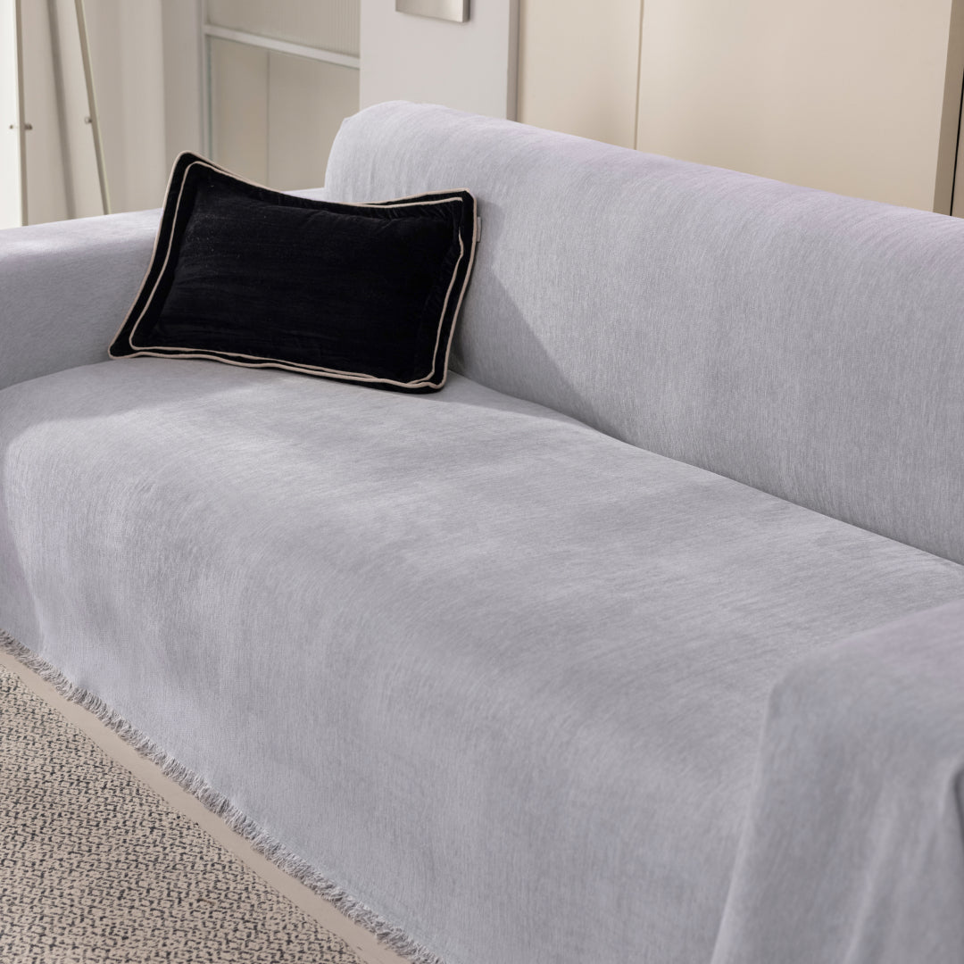 Angled view of a sofa covered in the Sesame Sophie Plush Magic Sofa Blanket, fringed edge visible