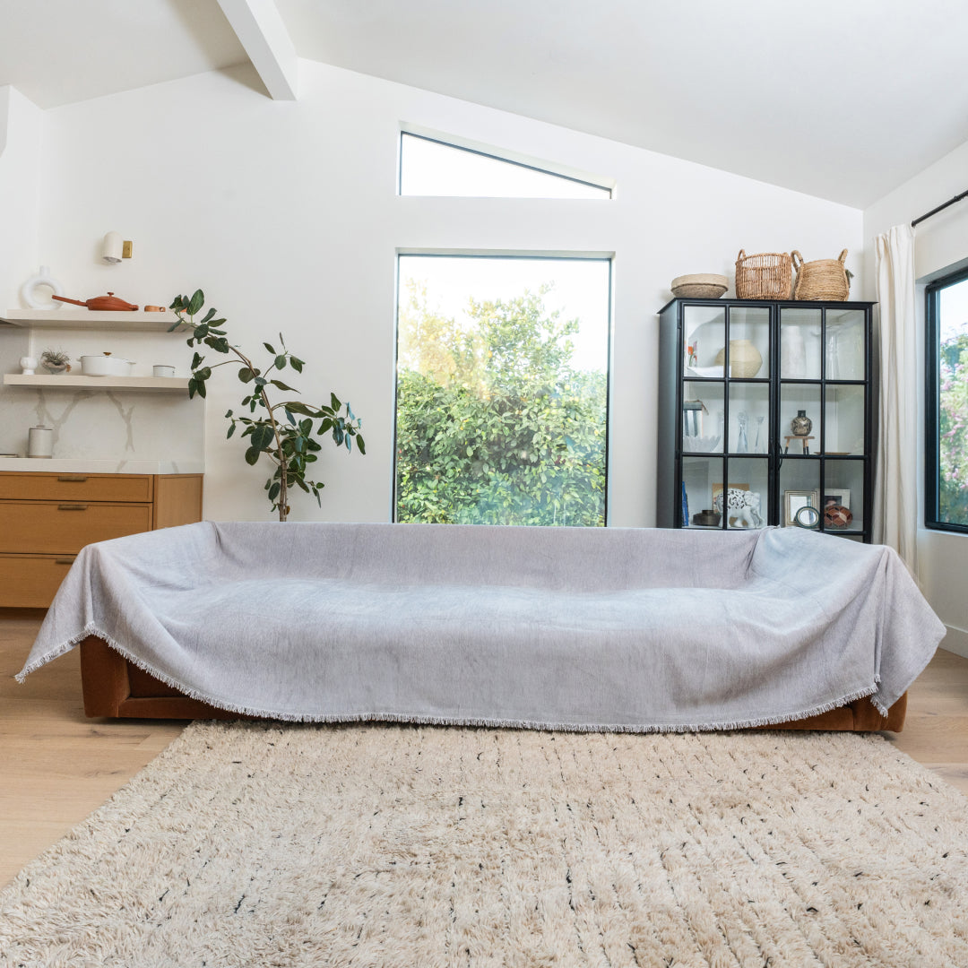Sesame Sophie Plush Magic Sofa Blanket covering a long sofa in a bright living room