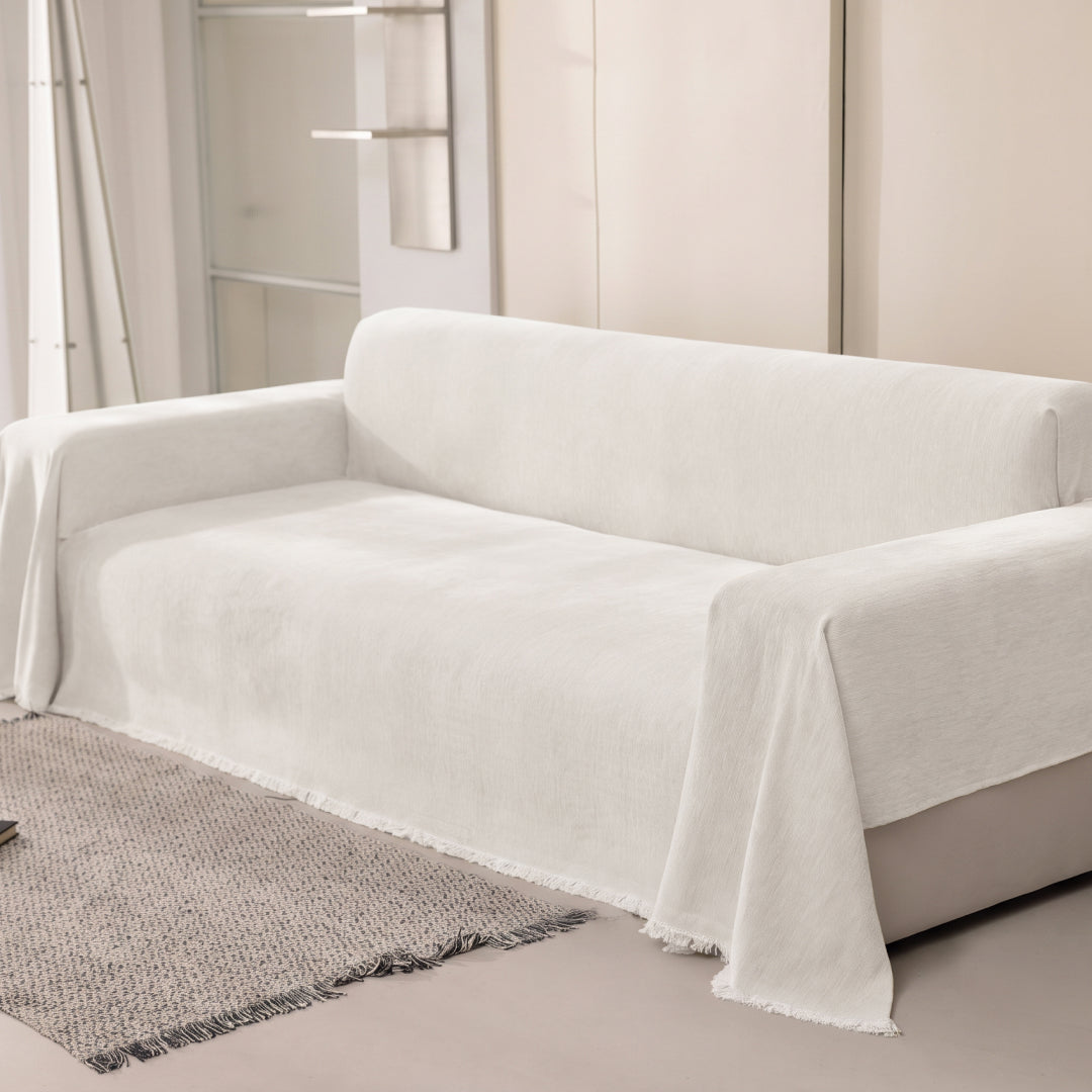 Angled view of a sofa covered in the Vanilla Sophie Plush Magic Sofa Blanket, fringed edge visible