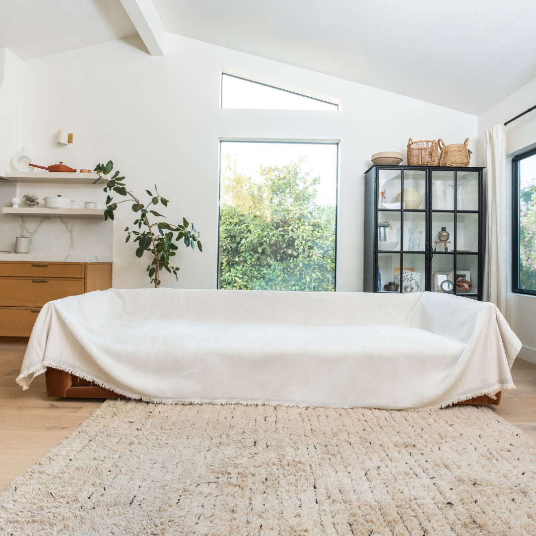 Vanilla Sophie Plush Magic Sofa Blanket covering a long sofa in a bright living room