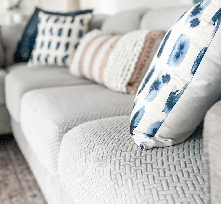Light grey sofa with textured stretch cushion covers and blue, white and blush throw pillows