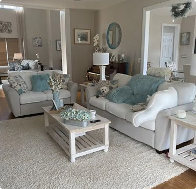Living room with two off-white sofas, teal cushions and a white wooden coffee table on a shaggy rug
