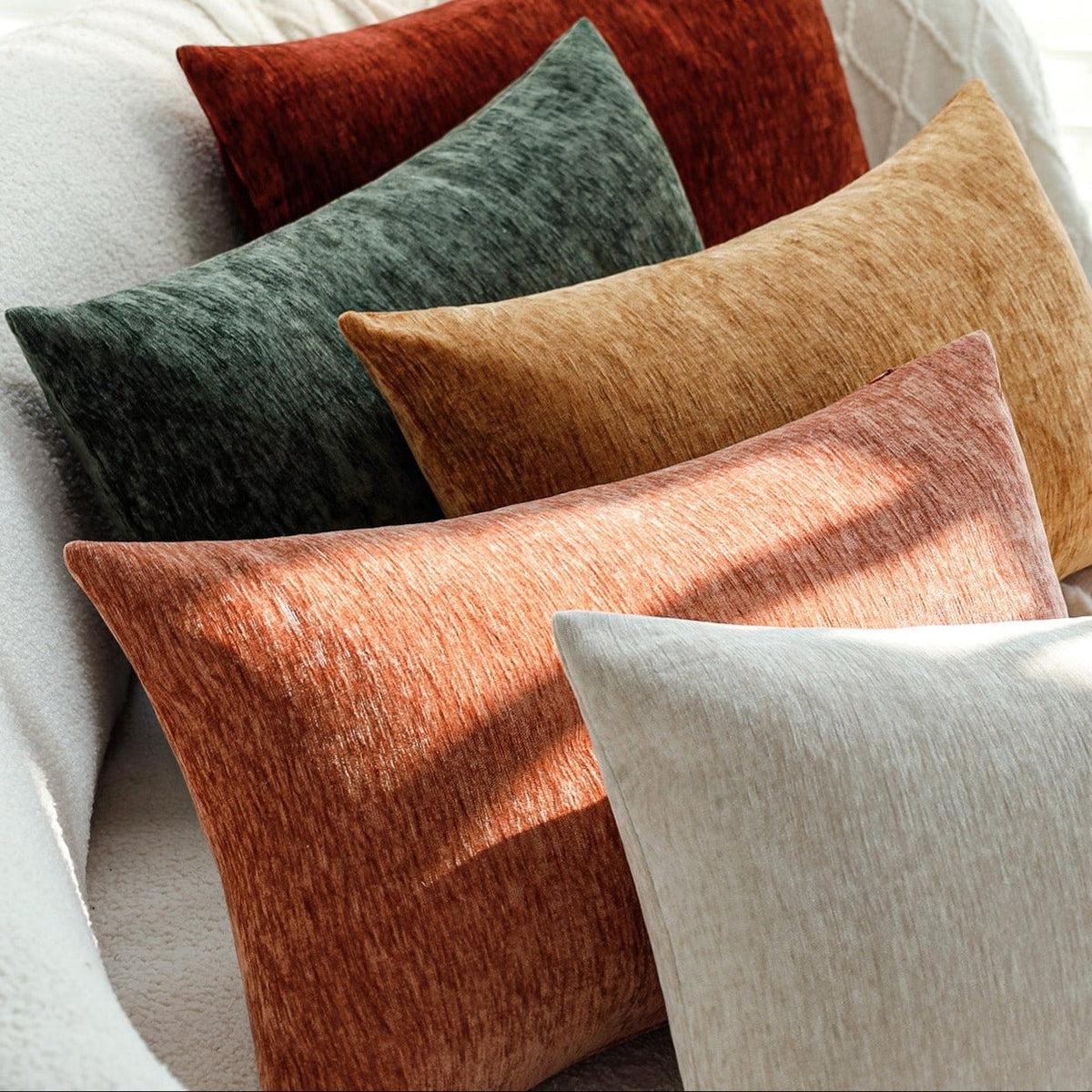 Close-up of Woody lumbar pillow covers in red, green, mustard, terracotta and light grey on a white sofa