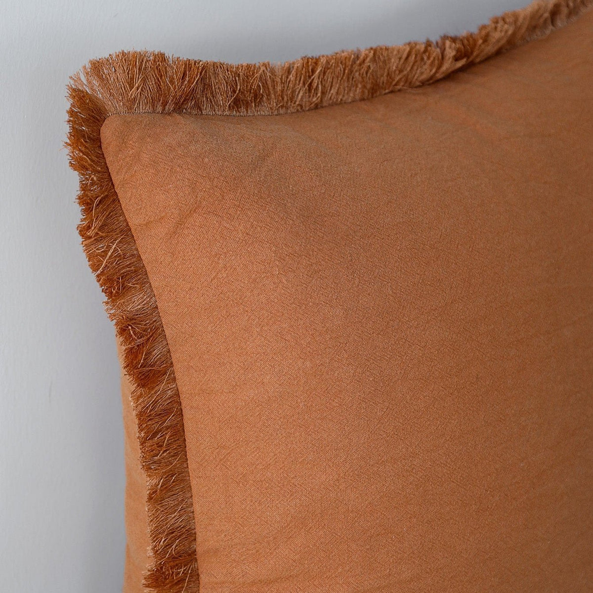 Close-up of a Fringe pillow cover in Rust showing the fringed edge