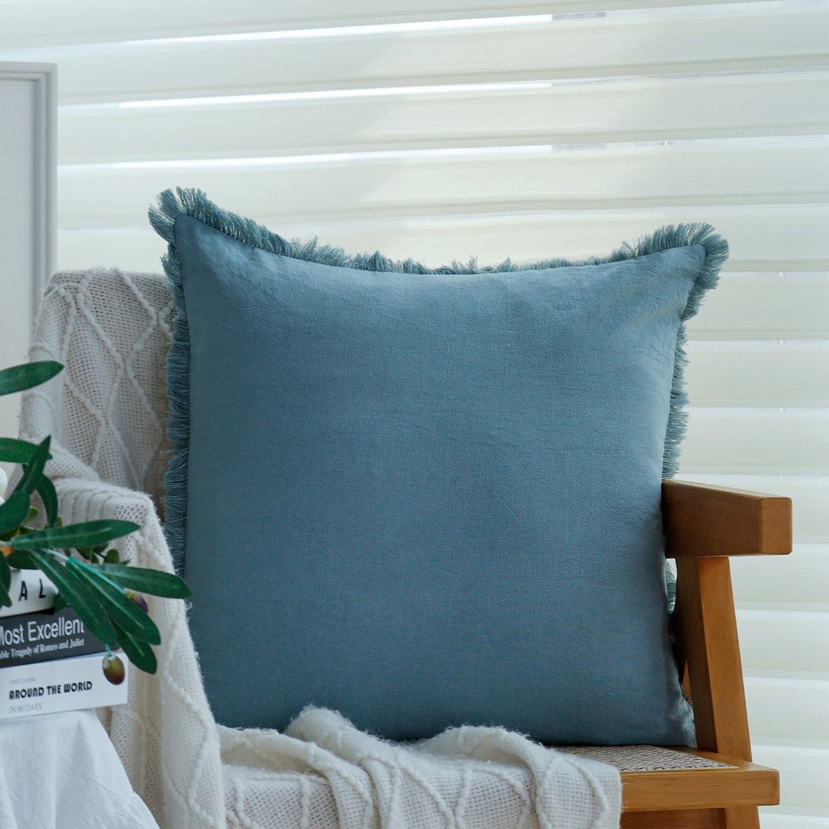 Fringe pillow cover in Cobalt on a wooden armchair with a white knit throw