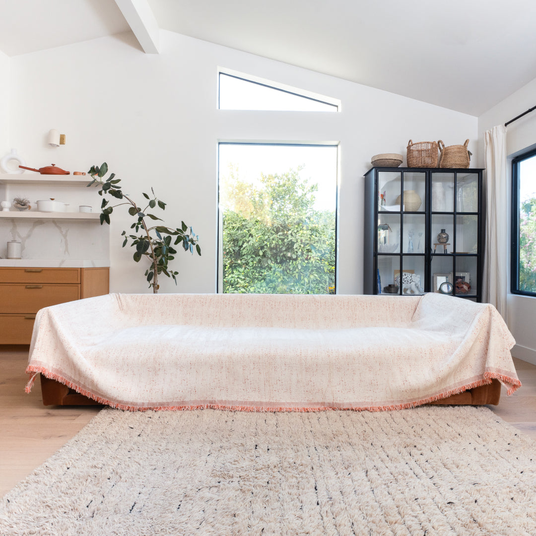 Cinnamon Iris Sprinkle Magic Sofa Blanket over a long sofa in a bright living room with a shaggy rug