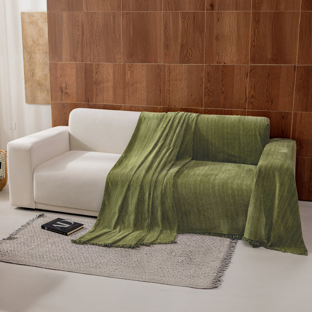 Kale Lena Herring Magic Sofa Blanket draped over half of a cream sofa