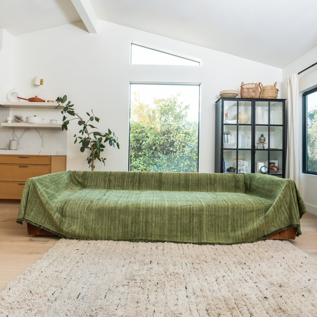 Kale Lena Herring Magic Sofa Blanket covering a long sofa in a bright living room