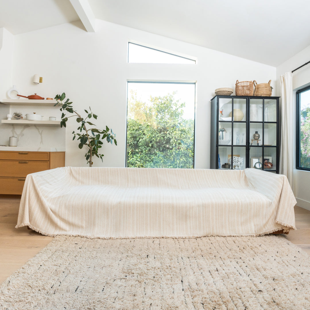 Latte Lena Herring Magic Sofa Blanket covering a long sofa in a bright living room