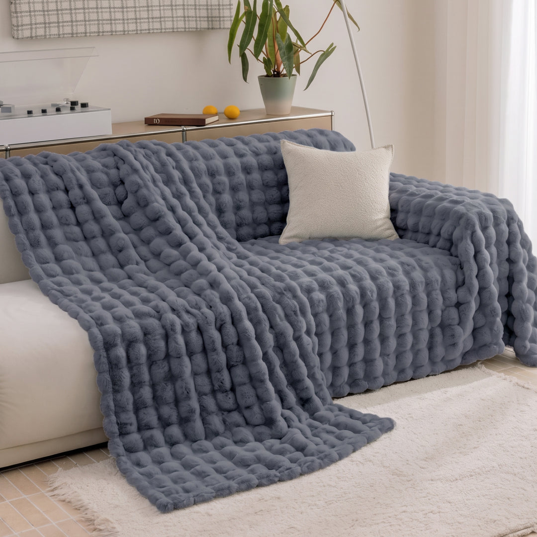 Black Sesame Nora Mink Magic Sofa Blanket placed halfway over a sofa