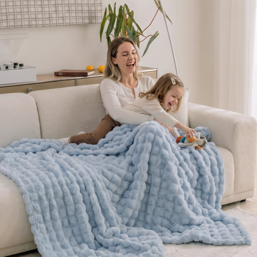 Person lounging on a sofa covered in the Celtic Salt Nora Mink Magic Sofa Blanket