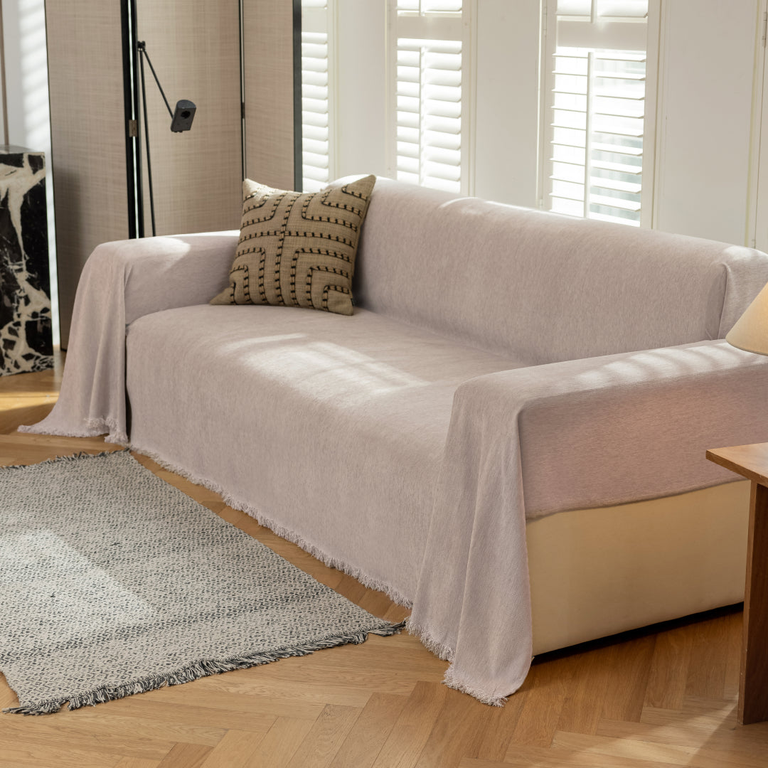 Angled view of a sofa covered in the Cookie Sophie Plush Magic Sofa Blanket, fringed edge visible