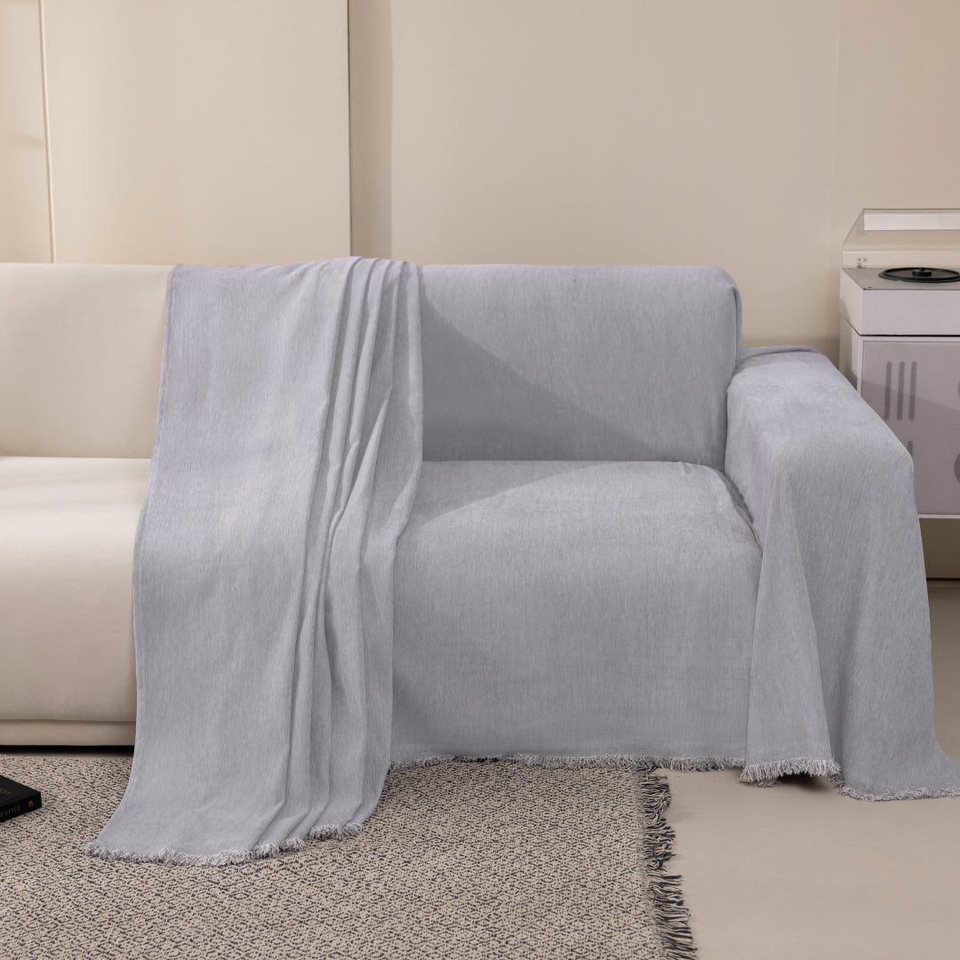 Sesame Sophie Plush Magic Sofa Blanket draped over one seat of a cream sofa