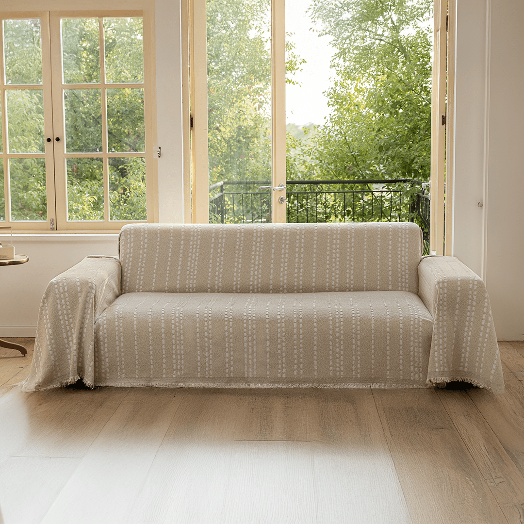 Vanilla Noah Stitch Magic Sofa Blanket draped over a sofa in a living room