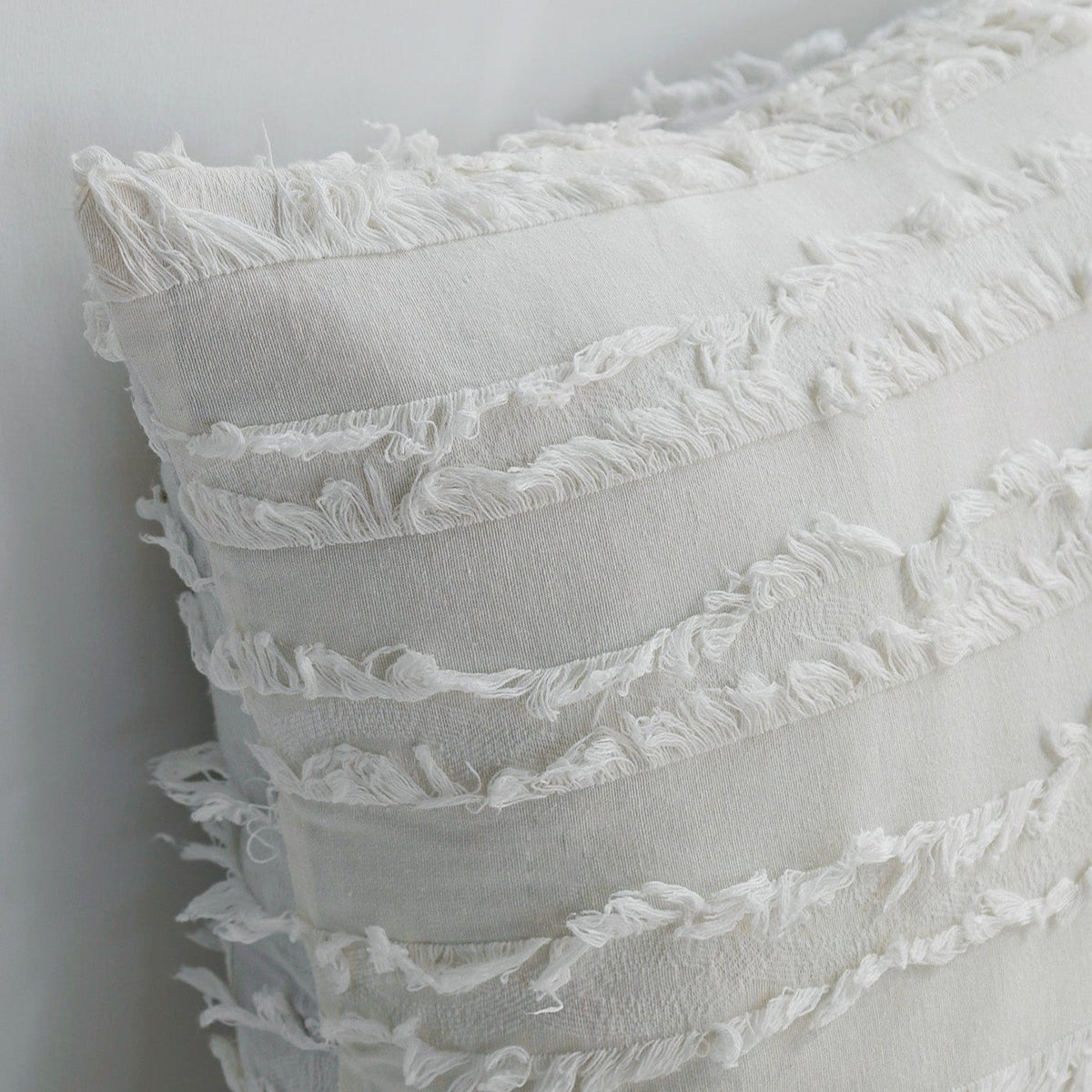 Close-up of the fringed stripes on an off-white Reeve pillow cover