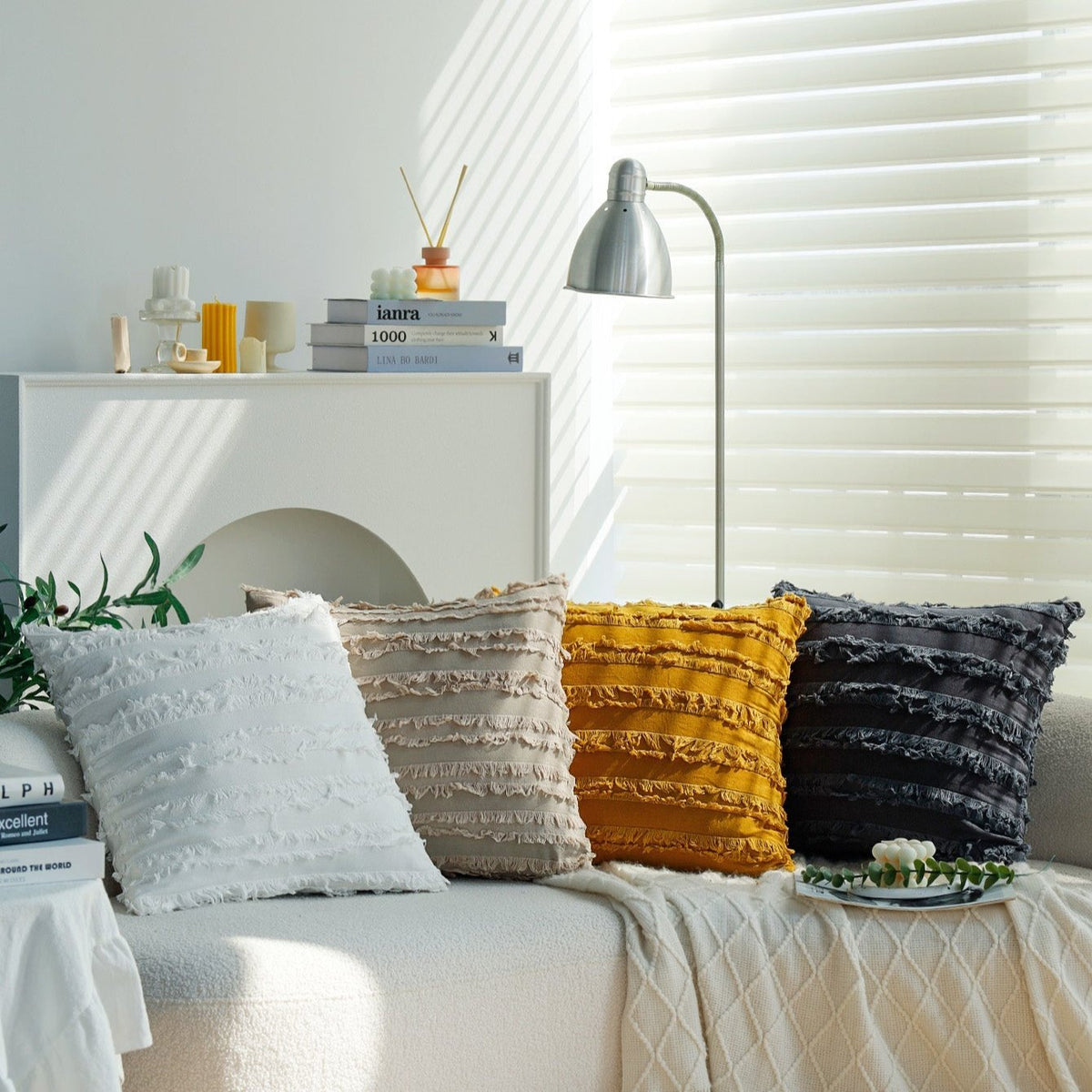 Reeve pillow covers in Pearl, Tan, Mustard and Ash on a white sofa by a window